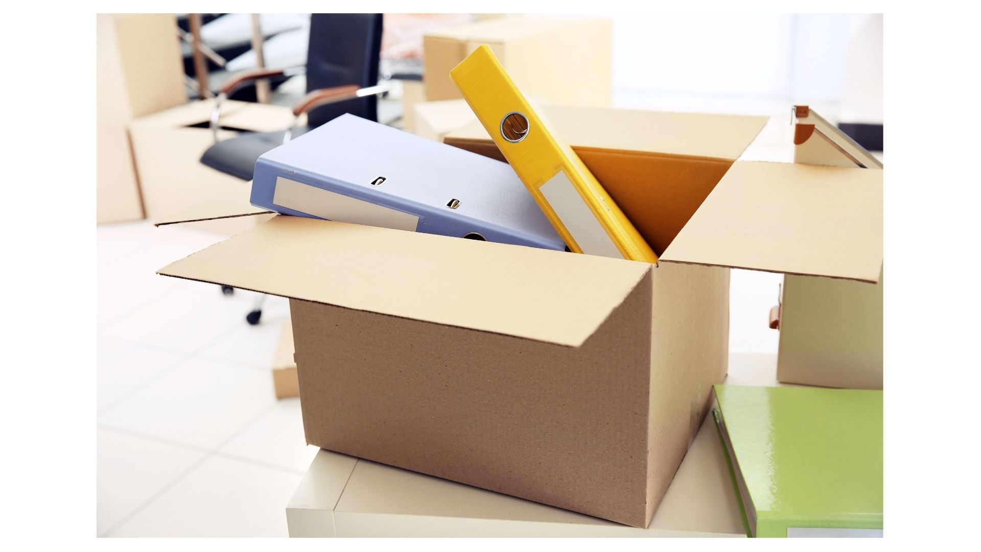 Cardboard moving box filled with binders and folders in an office mid-PCS pack-out