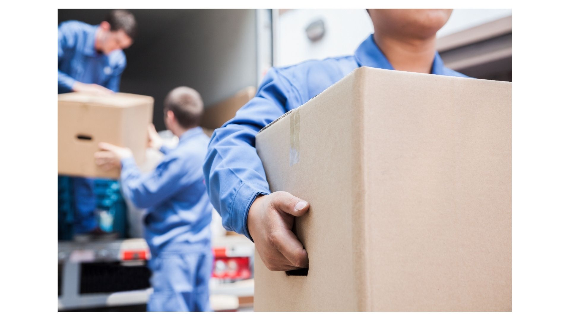 Professional movers in blue uniforms carrying cardboard boxes from a moving truck on a hot San Antonio day